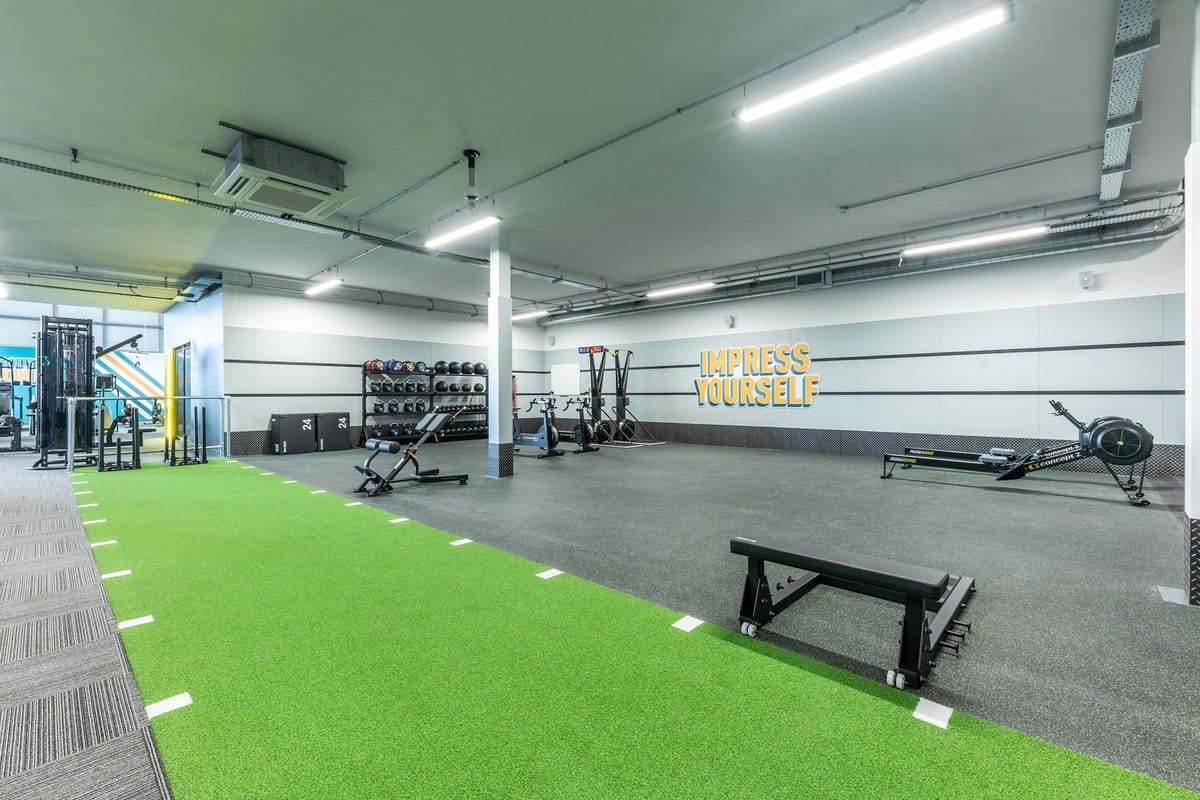 PureGym Tamworth: Free weights, benches, green turf area, and fitness equipment in an indoor gym space.