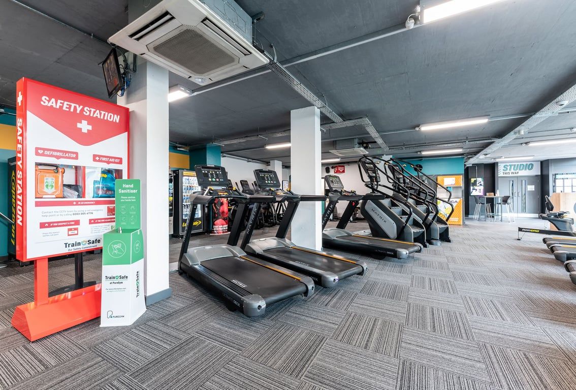 PureGym London Finsbury Park: Rows of treadmills, safety station kiosk, and air conditioning units overhead.