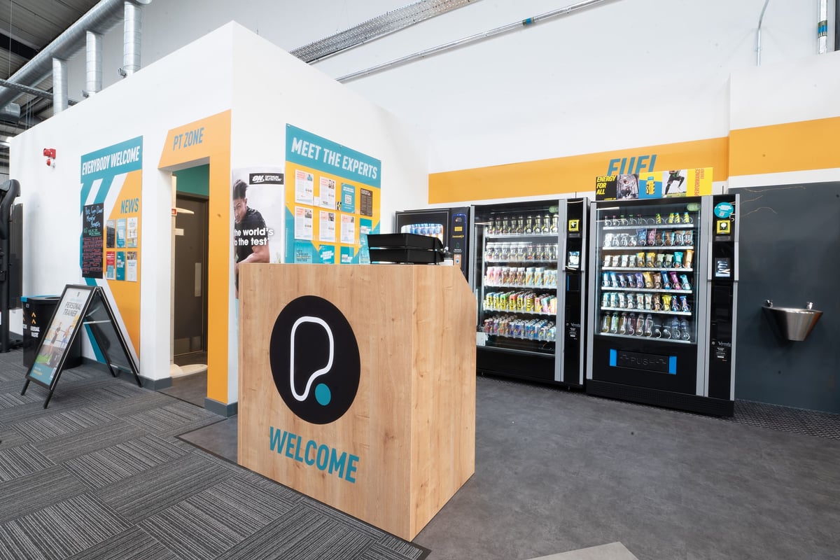 PureGym Dover: Vending machines, welcome sign, promotional displays inside a gym's reception area.