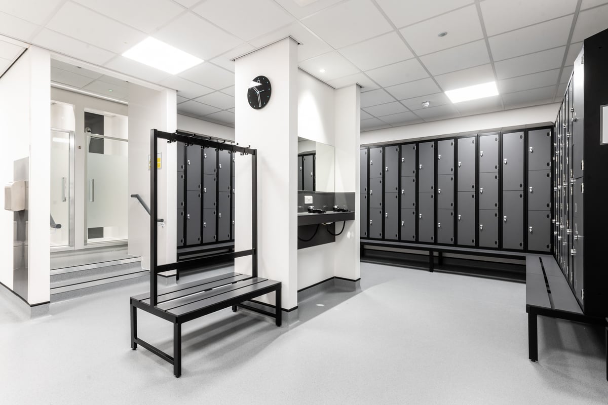 PureGym Peterborough Brotherhood Retail Park: Rows of lockers, benches, and entry gates in a changing room interior.