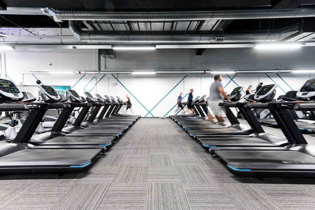 PureGym Hemel Hempstead: Rows of treadmills inside a bright gym space with blurred figures exercising.