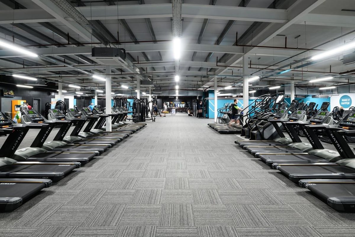 PureGym Cambridge Grafton Centre: Rows of treadmills, ellipticals, and exercise bikes inside a brightly lit gym facility.
