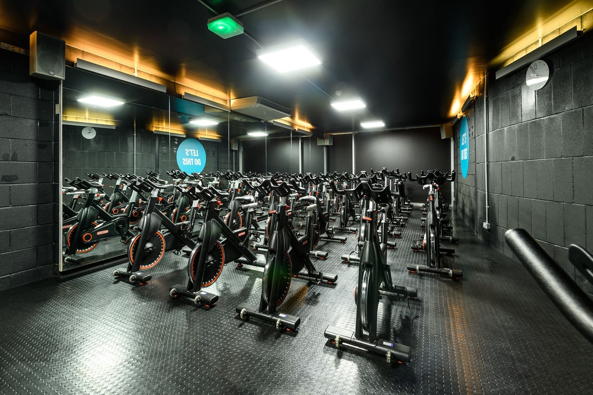 PureGym London Borough: Rows of stationary cycles inside a dimly-lit indoor cycling studio.