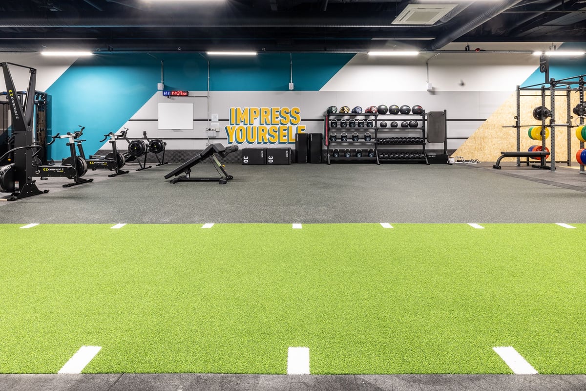 PureGym Hartlepool: Turf area, weight racks, sled rails, dumbbells, and resistance machines in a gym studio.