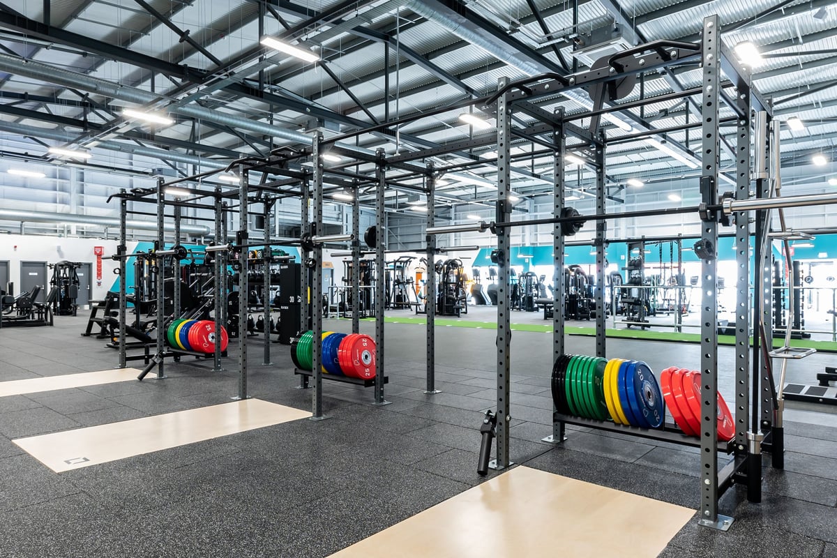 PureGym Ipswich Ravenswood: Bodyweight racks, barbells, weight plates, and rubberized flooring inside a well-lit gym space.
