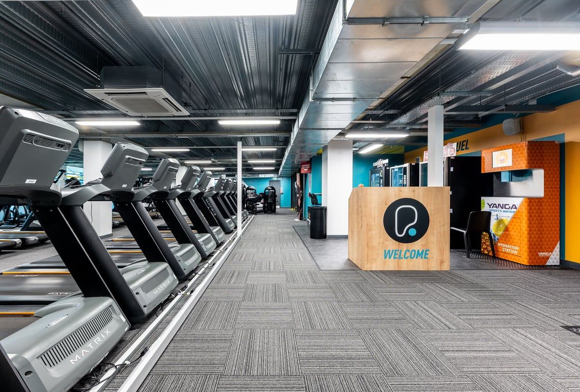 PureGym Newcastle Eldon Garden: Rows of treadmills, welcome sign, and ventilation ducts create a modern gym ambience.