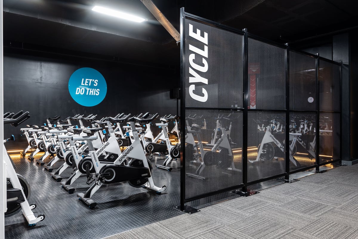 PureGym Norwich Castle Mall: Rows of spin bikes, workout area with mirrors, weight plate storage racks.