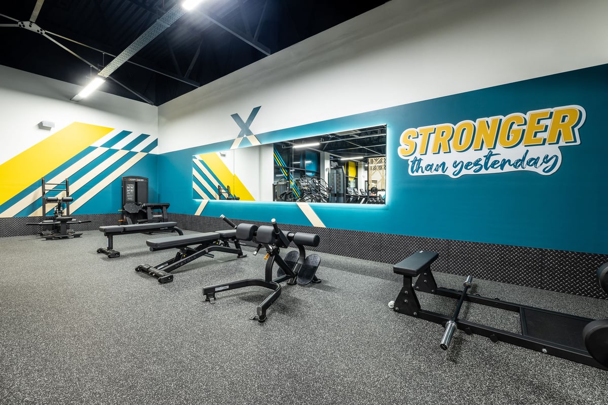 PureGym Washington: Weight benches, free weights, rubberized flooring inside gym with motivational wall graphics.