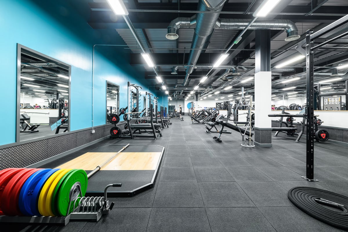 PureGym Newry: Gym interior with weight plates, benches, resistance machines, and framed motivational imagery on walls.