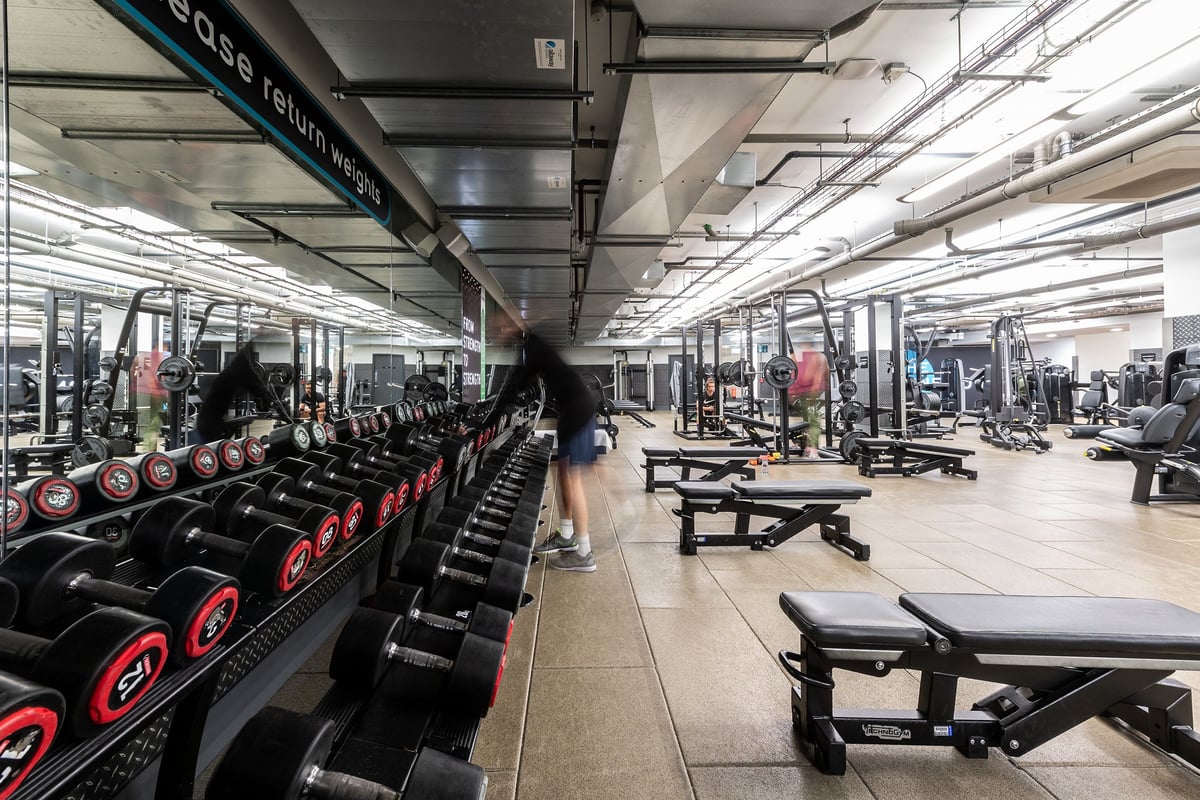 PureGym London Aldgate: Rows of dumbbell racks, benches, mirrors, and resistance equipment inside a gym.