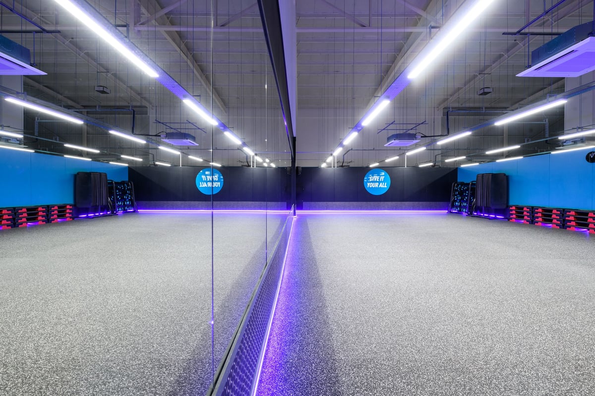 PureGym Nottingham Castle Marina: Rows of blue cable machine stations, purple lighting, and rubberized grey flooring.