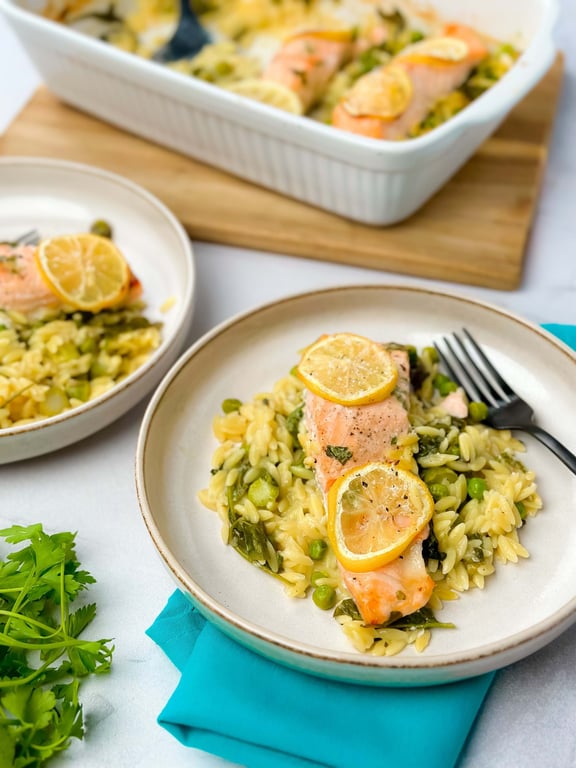 Salmon fillet with lemon slices served on orzo pasta with peas and greens
