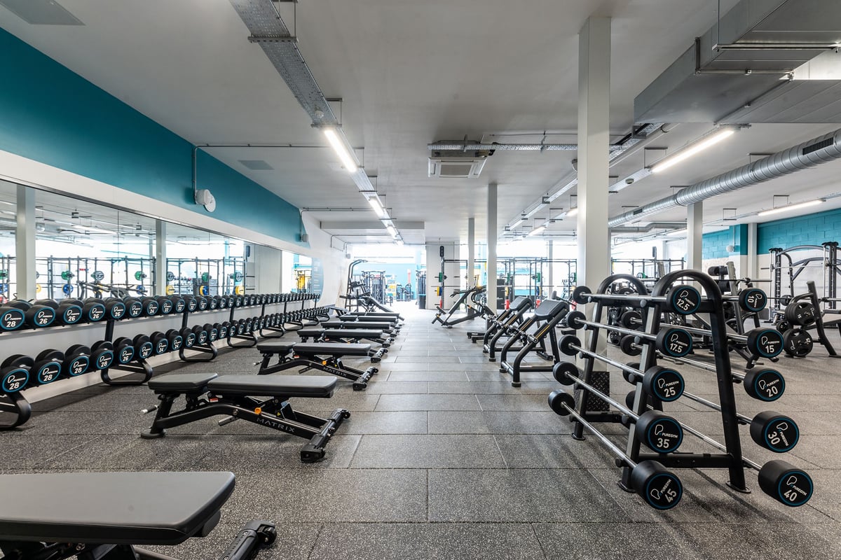 PureGym Dewsbury: Rows of weight benches, free weights, and strength equipment in a bright gym interior.