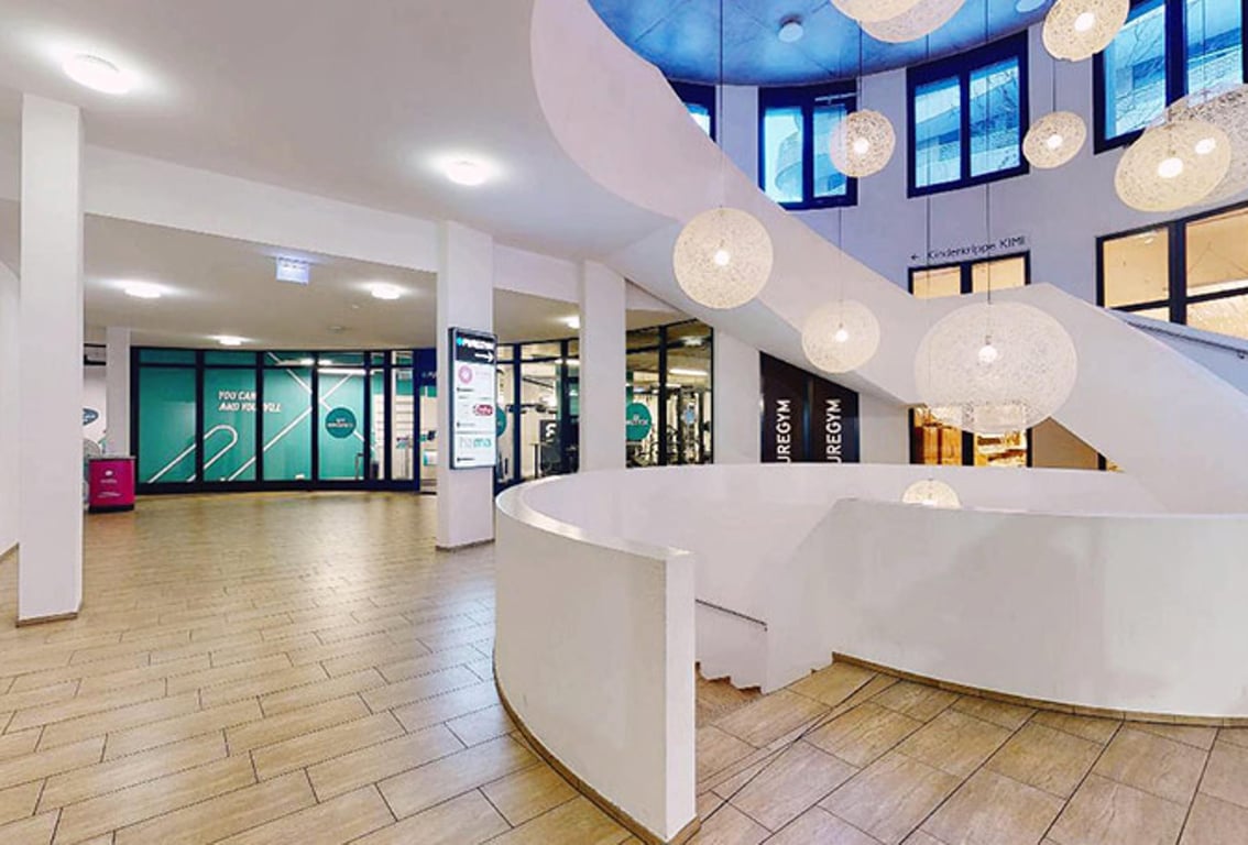 Puregym Chur: Lobbybereich mit Kugelleuchten und Rezeptionstischen.