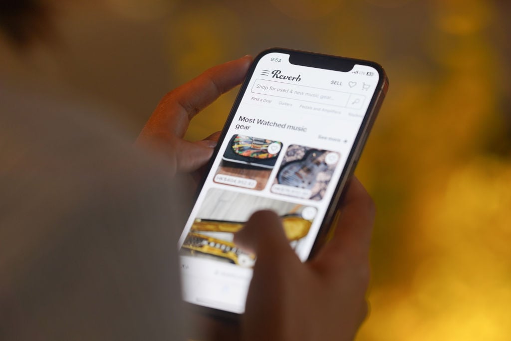 A woman browses Reverb on her smartphone for online shopping