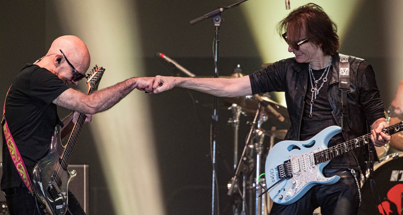 Joe Satriani [left] fistbumps Steve Vai onstage as the pair perform together onstage with their Ibanez signature guitars