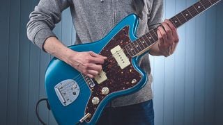 Person playing a powerchord on an electric guitar