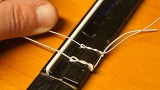 Close up of strings on a classical guitar bridge
