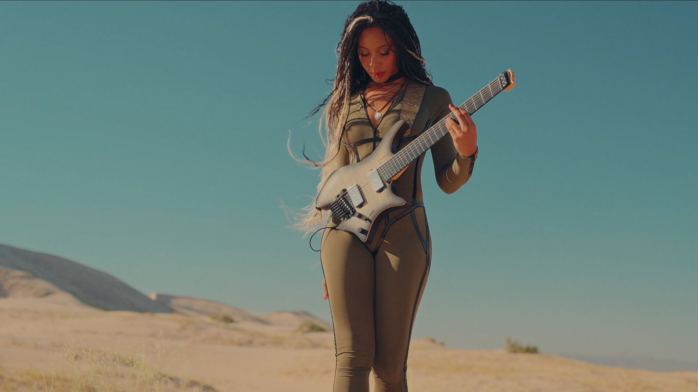 Chena plays a headless guitar in the desert