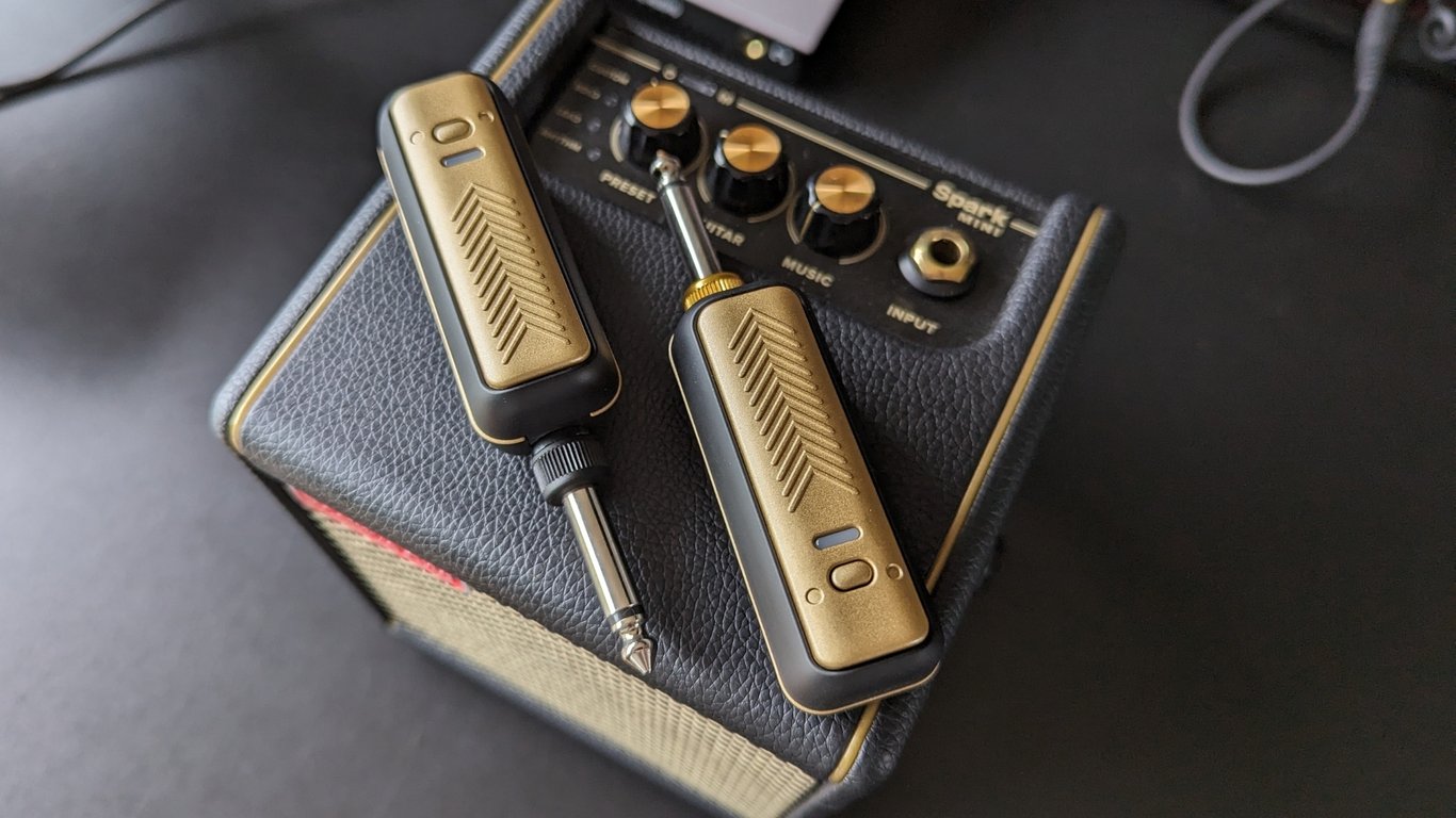 A Positive Grid Spark Link transmitter and receiver on top of a Positive Grid Spark Mini practice amp