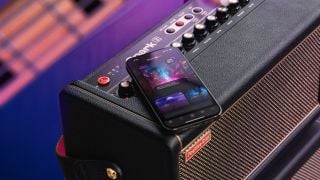 A smartphone displaying Positive Grid's Spark AI on top of a Spark 2 guitar amp