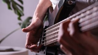 Close-up of hands practicing slap technique on electric bass.