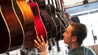 Mn in a guitar shopping perusing a range of acoustic guitars