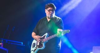 Will Sergeant of Echo & the Bunneymen plays a Daphne Blue Jazzmaster on a stage lit in blue-purple.