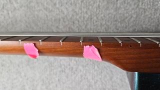 Pink tape on the side of a guitar neck