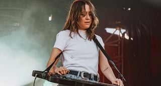 Megal Lovell wears a white T-shirt as she performs outdoors with her lap-steel. For new album Bloom, Megan looked to lap steel luminary David&nbsp;Lindley for inspiration on tones and backline&nbsp;choices.