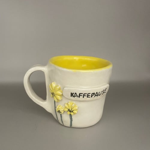 Kop gul indvendig og  med gule blomster. Tekst KAFFEPAUSE