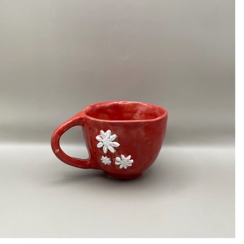 Rød kop med hvide blomster