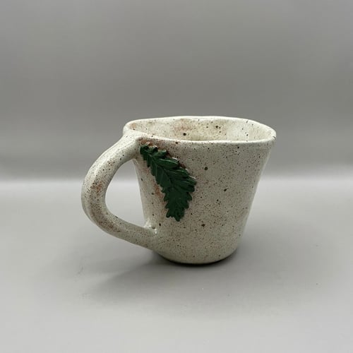 Beige kop med grønt blad