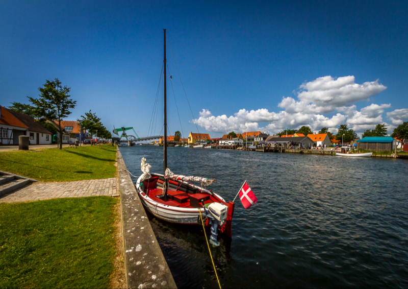 En lille sejlbåd ligger til kaj i kanalen på Enø en smuk sommerdag - billede 1