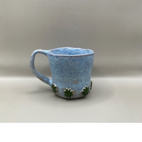 Lyseblå kop med grønne blomster