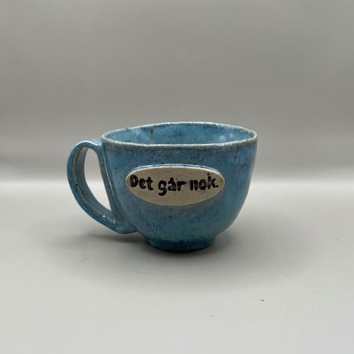 Kop med tekst “Det går nok” i blå nuance