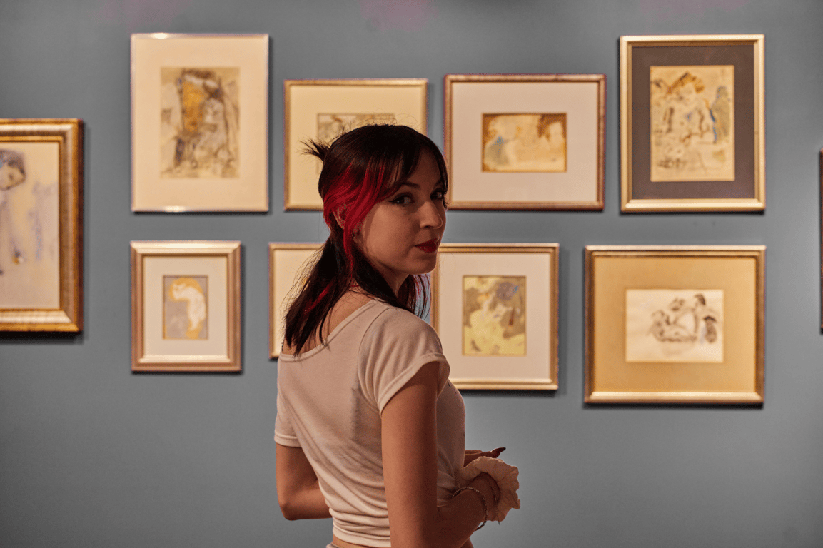 An elegant private art collection in a wood-paneled study with framed paintings and antique furnishings