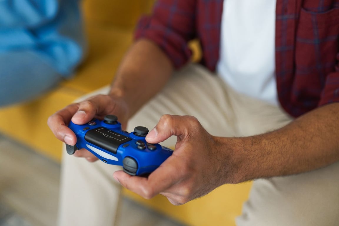 快適な室内のソファで青いワイヤレスゲームコントローラーを持つ手元