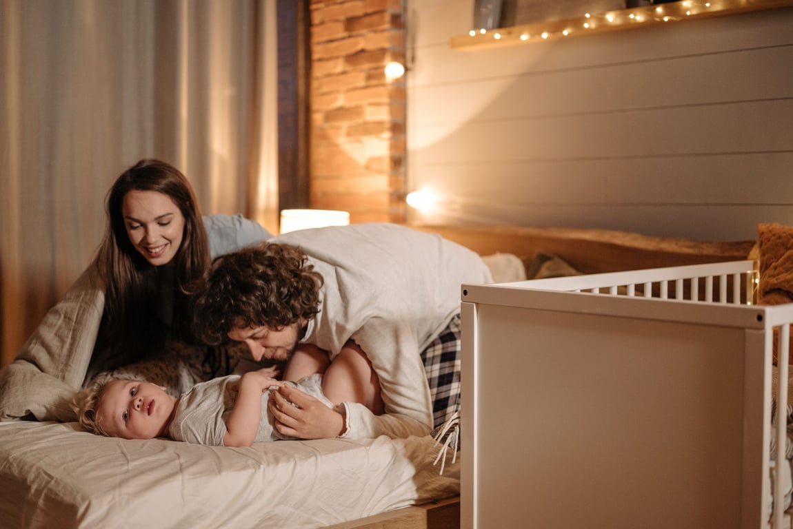 A joyful family moment with parents and child resting together in a warmly lit bedroom
