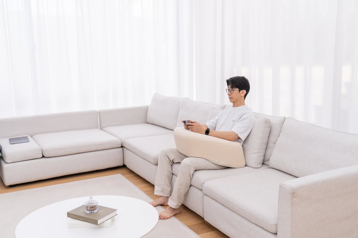Close-up of beige LevelUp Cushion supporting arms while using a laptop on a sofa
