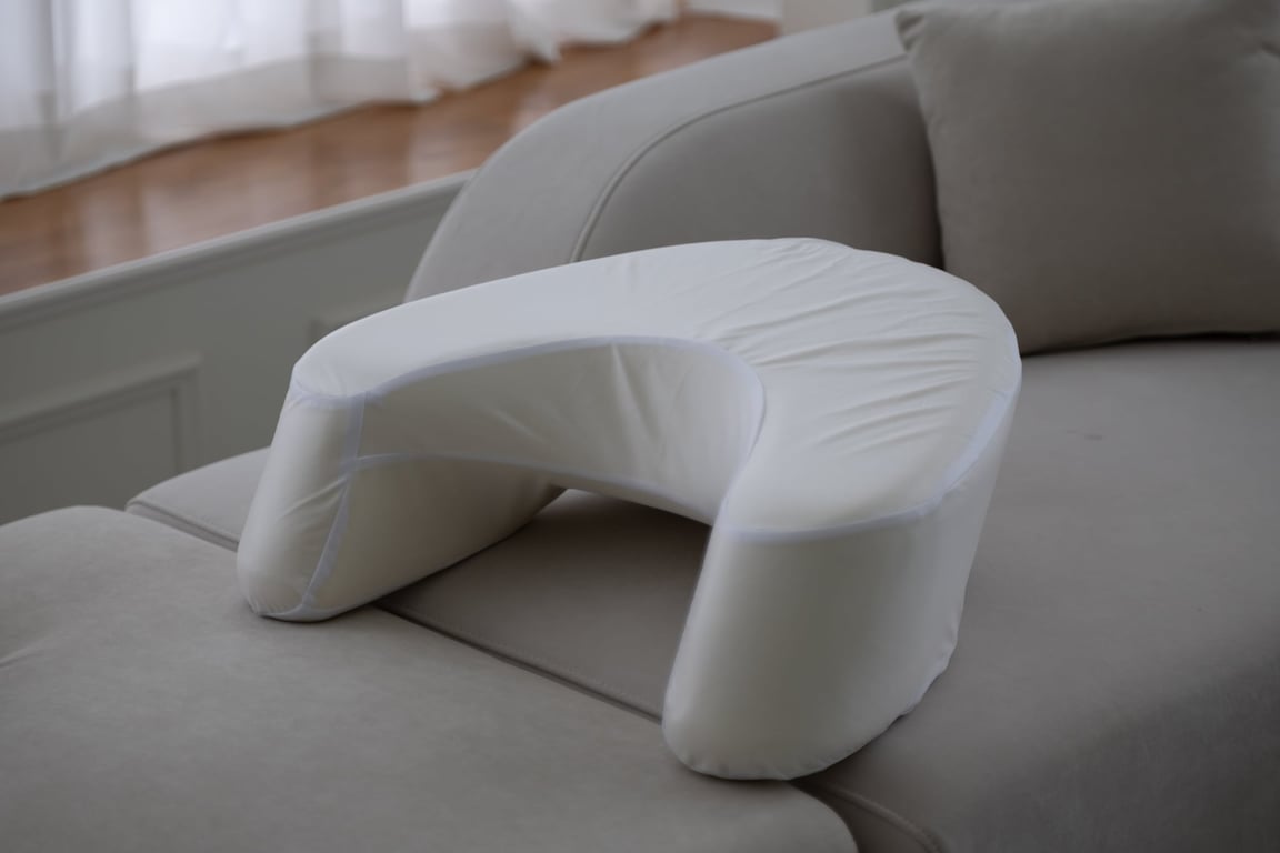 Beige LevelUp Cushion placed on a sofa, demonstrating its U-shaped design for arm support to improve posture