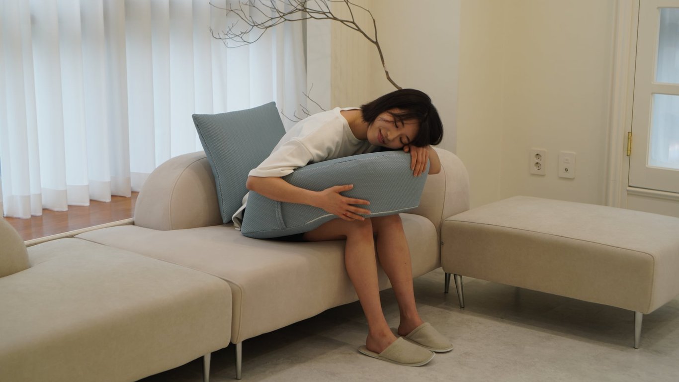 레벨업쿠션을 양팔로 꼭 껴안고 눈을 감아 편안한 휴식을 취하는 여성의 모습