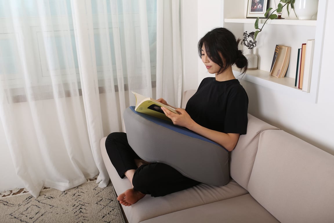 ソファで読書中に両腕をレベルアップクッションで支えている様子