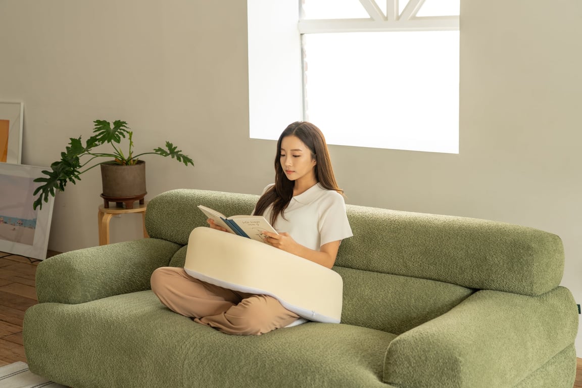 クッションの上に腕を乗せて本を読む女性