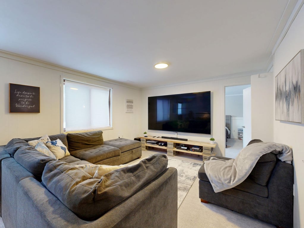 Spacious living room with a large gray sectional sofa and TV, representing a comfortable Western home environment for cancer care