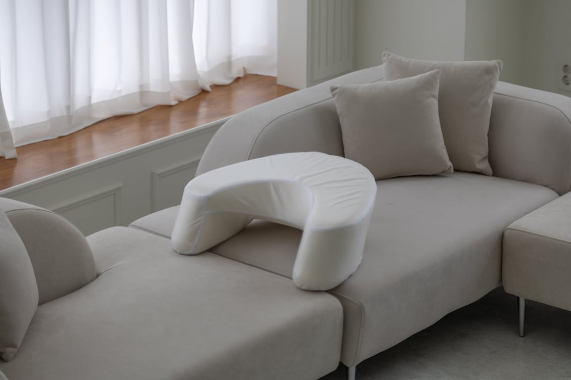 소파 팔걸이에 위치한 베이지색 펌플렉스 레벨업쿠션(LC-CHAIR)