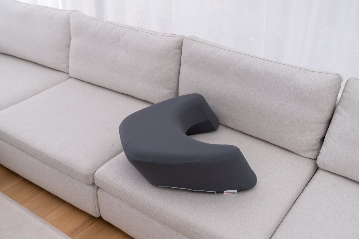 Dark gray U-shaped LevelUp Cushion placed neatly on a light gray sofa