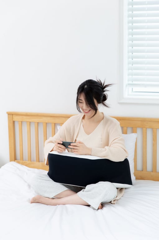 무릎 위에 레벨업쿠션을 올려놓고 팔을 편안하게 얹은 채 스마트폰을 사용하는 여성의 모습