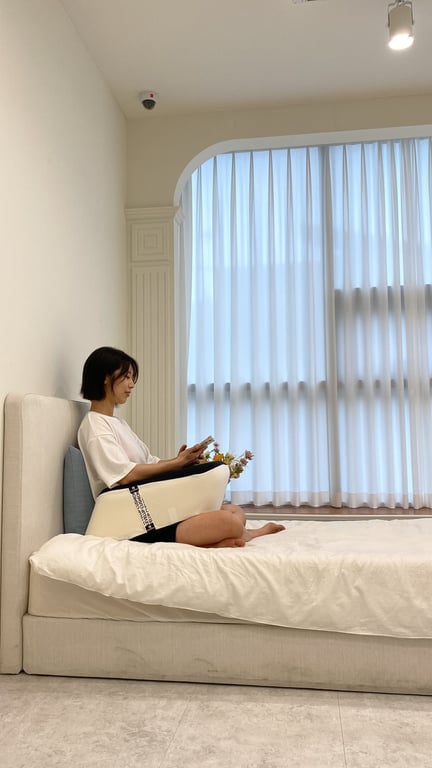 침실 바닥이나 낮은 곳에 앉아 스마트폰이나 태블릿을 시청할 때 무릎 위에 쿠션을 올려놓고 편안한 자세로 휴식하는 모습