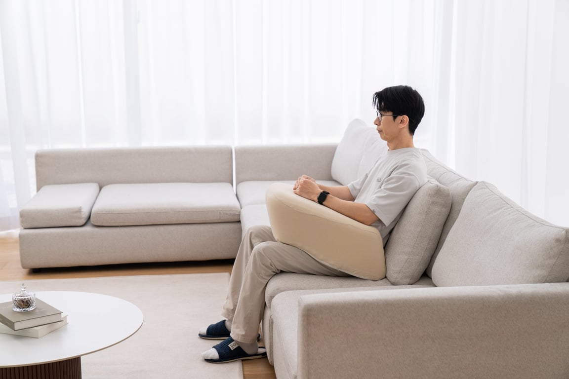 낮은 소파에 앉아 레벨업쿠션에 팔꿈치를 올리고 휴식하는 남성의 손과 쿠션 디테일